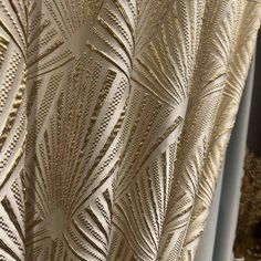 an intricately designed curtain is shown in gold and white colors, with large leaves on it