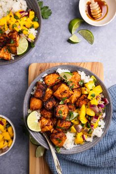 two bowls filled with chicken and pineapple salsa on top of rice next to a wooden cutting board