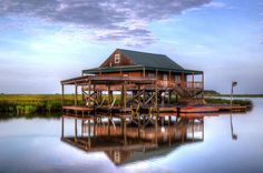 a house sitting on top of a lake next to a dock with a boat in the water