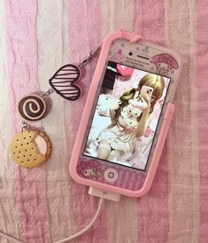 a cell phone is hooked up to a keychain on a pink blanket with two cookies