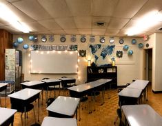 an empty classroom with desks, chairs and a projection screen on the wall in front of it