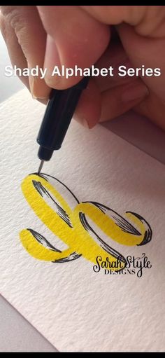 someone is using a pen to draw the letters e and q on paper with yellow ink