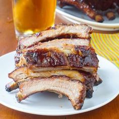 ribs on a white plate next to a glass of orange juice and a yellow napkin