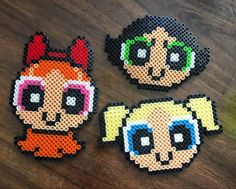 three perler bead coasters sitting on top of a wooden table