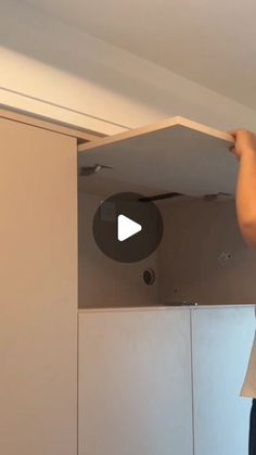 a man standing on top of a kitchen counter next to a white refrigerator freezer