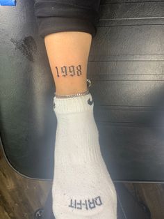 a person with a small tattoo on their left leg and the number 989 written on her right ankle