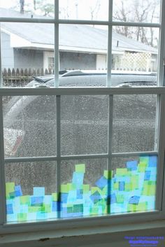 a window that has some colored sticky notes on the glass and it's raining outside