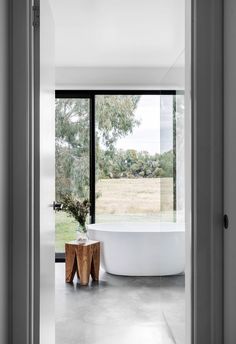 a white bath tub sitting next to a window in a bathroom under a large window