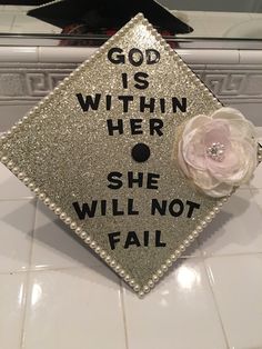 a graduation cap that says, god is within her she will not fail it on the floor