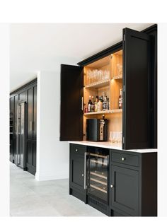 an empty kitchen with black cabinets and wine glasses on the counter top in front of it