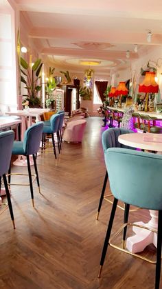 the interior of a restaurant with many tables and chairs in blue, pink, and yellow colors