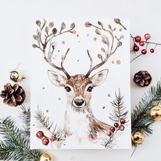 a christmas card with a deer's head surrounded by pine cones and evergreens