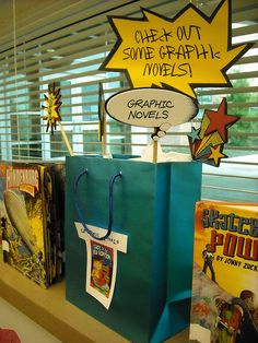 some books are sitting on a shelf in front of a window with the words open out some graphic novels