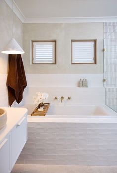 a white bathroom with two windows and a bathtub