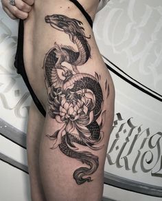 a woman's thigh with a dragon and flower tattoo on it