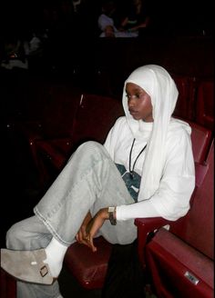 a woman sitting on top of a red chair next to a man in a white hoodie