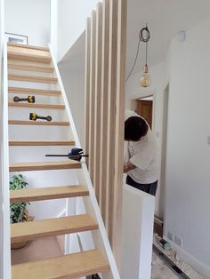 a man is working on some stairs in a room with white walls and wood flooring