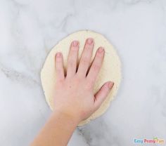 a person's hand on top of a pizza dough with one hand on it