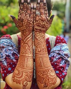 a woman holding her hands up to her face with hendi tattoos on it's arms