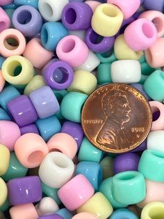 a penny sitting on top of a pile of small plastic bead beads in pastel colors