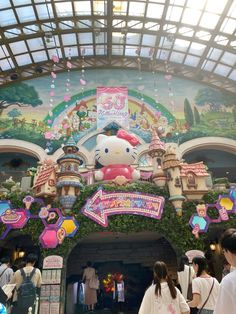 there are many people standing in front of the hello kitty entrance