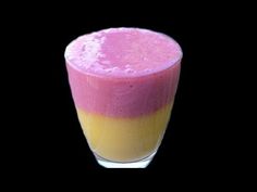 a pink and yellow smoothie in a glass on a black background with the top half turned down