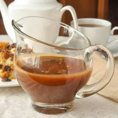 a glass pitcher filled with liquid sitting on top of a table next to plates of food