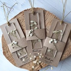 four tags with dried flowers on them sitting on a table