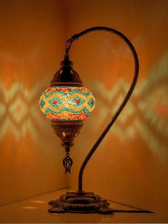 a lamp that is sitting on top of a table next to a wall with an intricate design