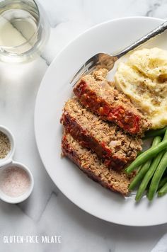 meatloaf, mashed potatoes and green beans on a plate next to a glass of milk