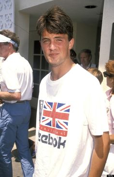 a man standing in front of a building wearing a t - shirt with the british flag on it