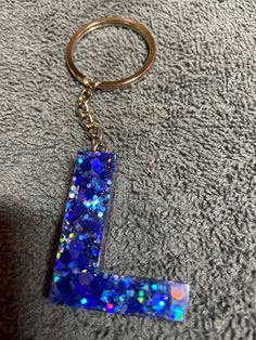 a keychain with a blue glitter letter on it sitting on top of a carpet