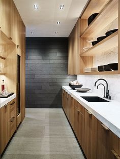 a long narrow kitchen with wooden cabinets and white counter tops, along with black accents