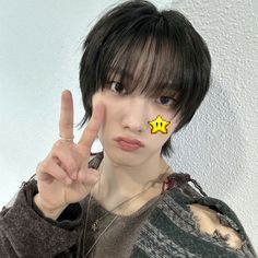 a young man making the peace sign with his hand and wearing a yellow star on his forehead