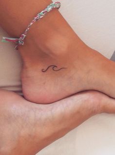 a woman's foot with a small wave tattoo on it