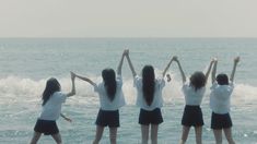 four girls standing on the beach with their arms in the air