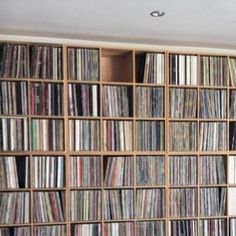 a room filled with lots of different types of records and cds on wooden shelving