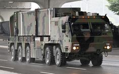 an army truck driving down the road under a bridge