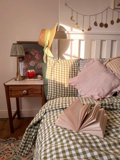 an open book sitting on top of a green and white checkered bedspread