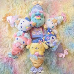 a group of stuffed animals laying on top of a colorful blanket with an ice cream cone in the middle