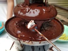 a chocolate cake with white frosting and blueberries on top is being drizzled by a spatula