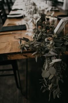 the table is set with wine glasses and greenery