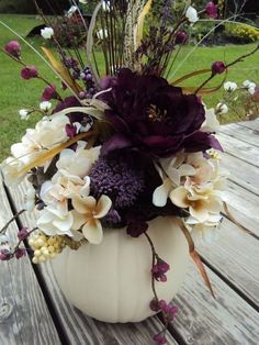 a white vase filled with flowers on top of a wooden table