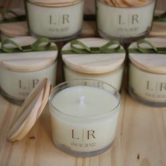 several candles are sitting on a table with green ribbon around them and one candle has a wooden lid