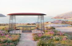 an empty picnic table in the middle of a field with wildflowers and mountains in the background