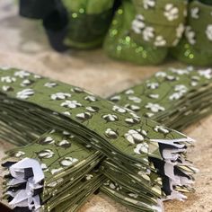 several pieces of green fabric with white flowers on them sitting on a counter top next to some vases