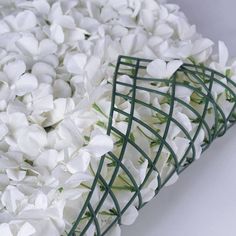 a bunch of white flowers that are in a vase on a table with green wire