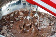 a mixing bowl filled with chocolate batter and whisk mixer attachments in it