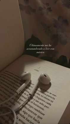 an open book with ear buds laying on top of it