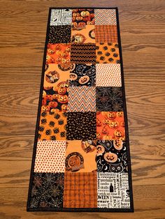 a table runner made out of patchwork and halloween themed items on top of a wooden floor